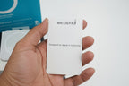 White card with text held by a hand, with a blurred background