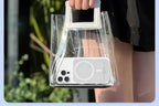 Clear handbag with a phone inside, held by a person against a blurred outdoor background.