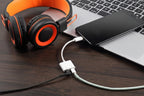 Headphones connected to a phone via a cable on a wooden surface