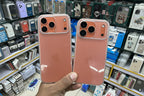 Two rose gold phone cases held in front of a store shelf with phone accessories.