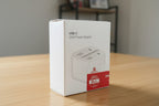 USB-C power adapter packaging on a wooden surface with a blurred background